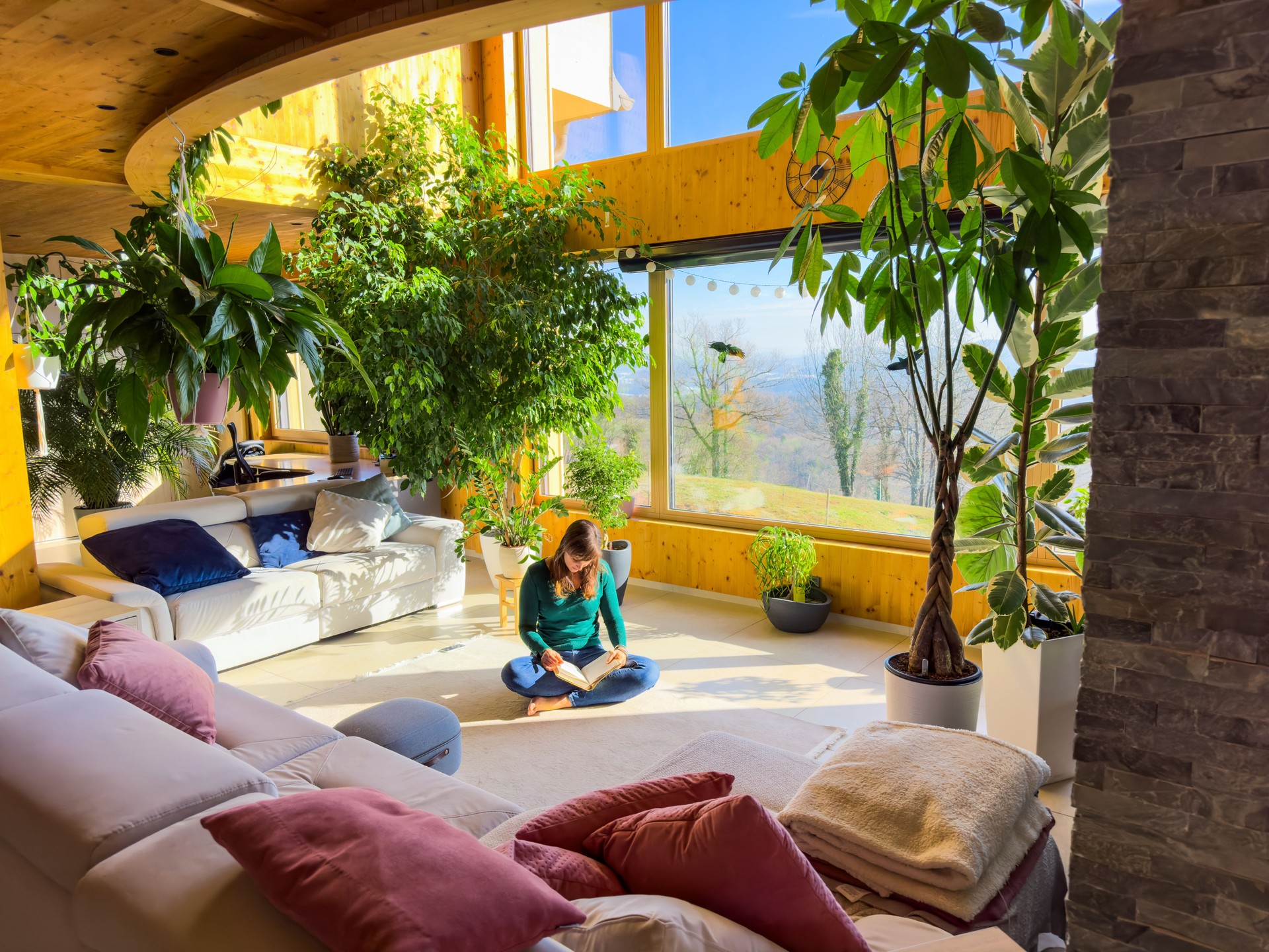 Woman with crossed legs sits on the floor of modern living room, reading a book